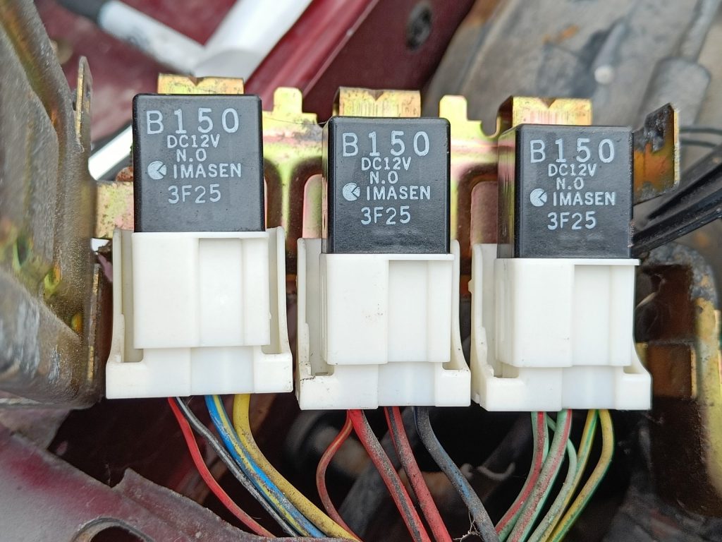 Image of relays locted between O/S wing and engine bay fuse box