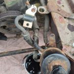 Image of unbolted power steering header tank draining into a bucket.
