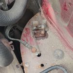 Image of clutch rigid pipe to rubber pipe connecting bracket at rear of engine bay.