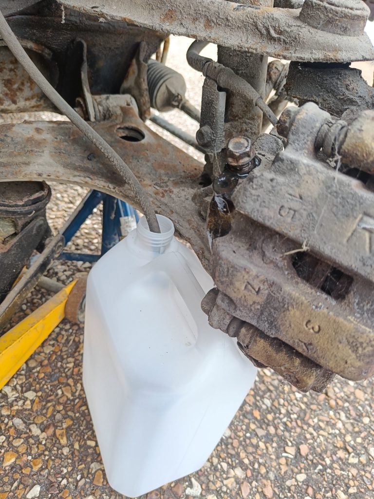 Image of draining the brake fluid into a plastic container.