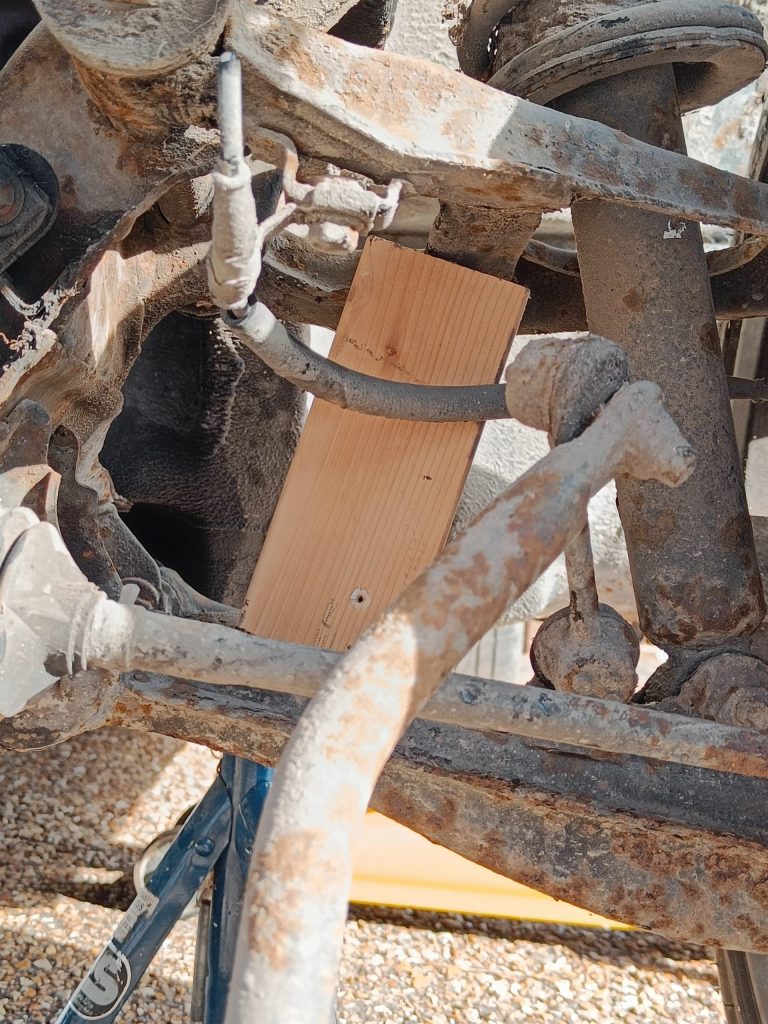 Image of wood block between front upper and lower wishbones.