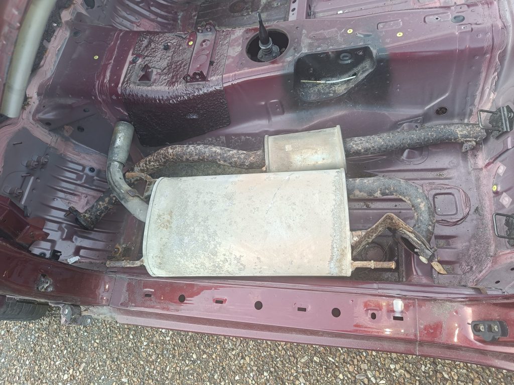 Image of rear sections of exhaust system in passenger footwell ready to scrap.