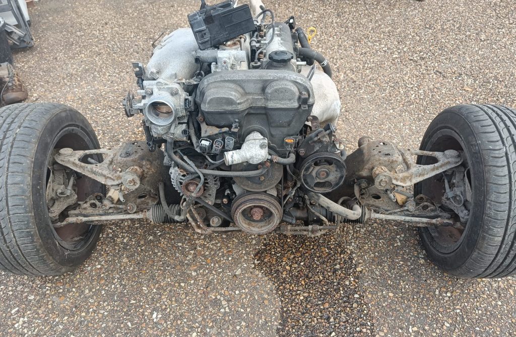 Image of engine, gearbox & front subframe after being rolled out from the body shell.