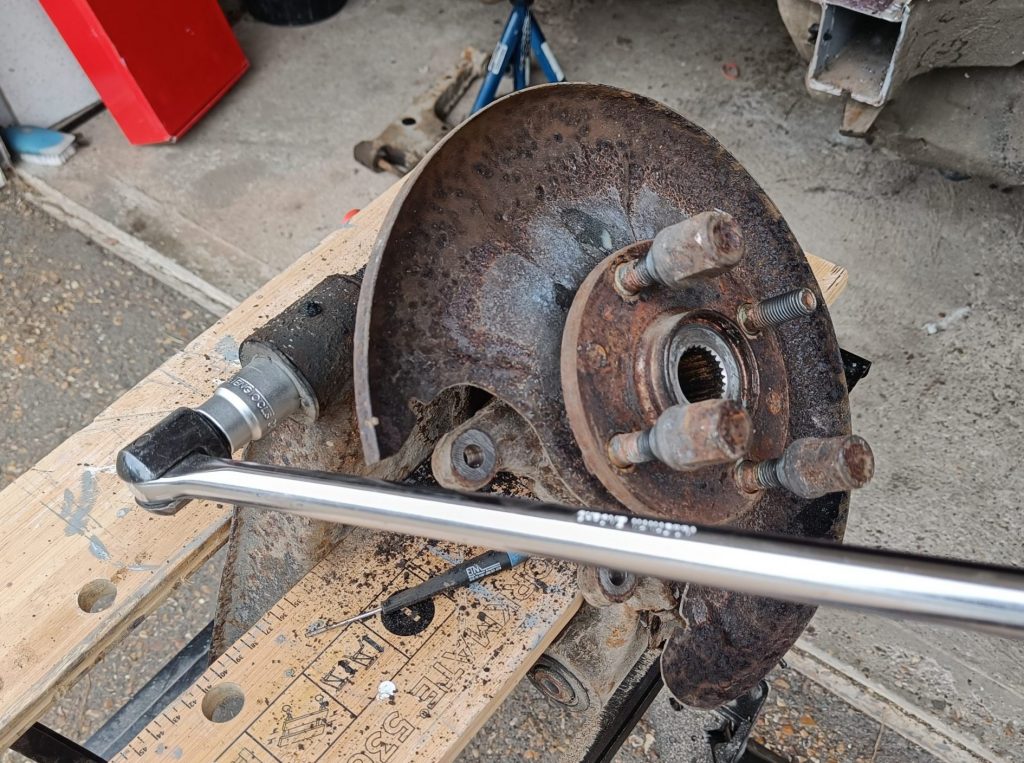 Image of lower rear wishbone bolt being initially rotated using a breaker bar and penetrating oil.