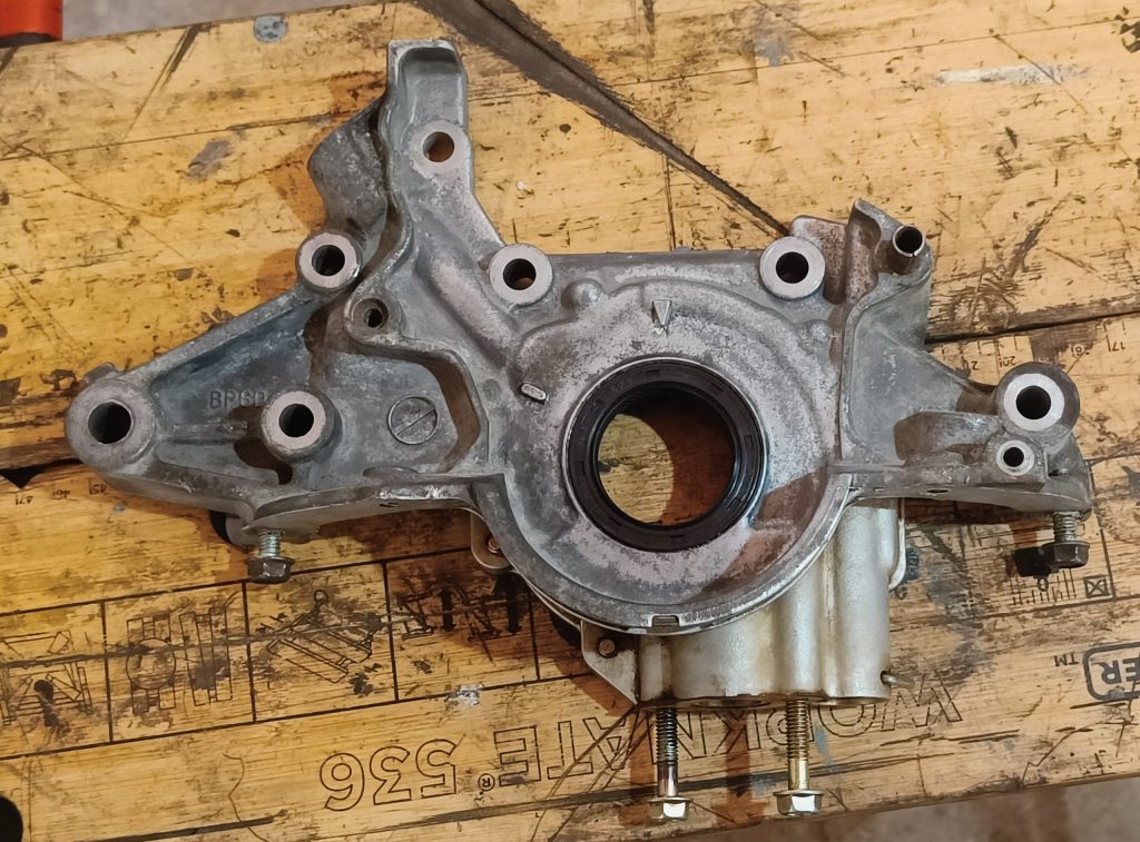 Image of oil pump removed to extricate a broken bolt and rusted in timing cover crush tubes.