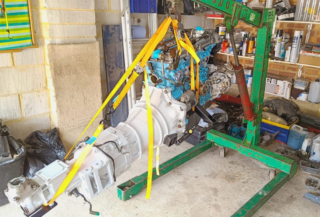 Image of engine and gearbox on hoist ready to be installed.