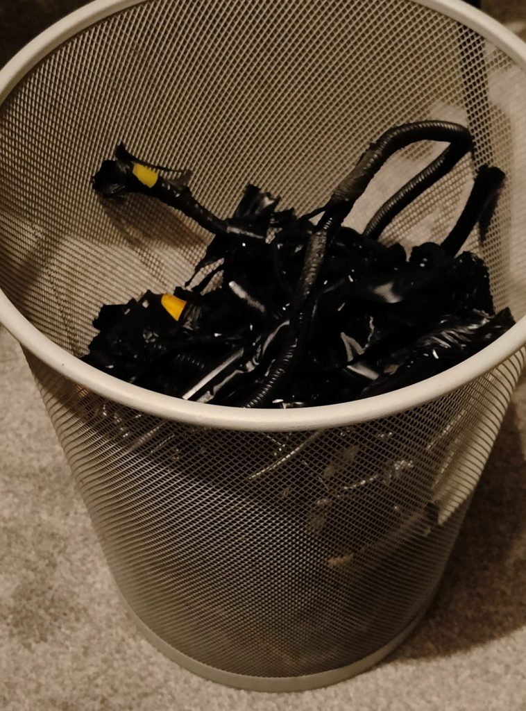Image of a bin full of removed loom tape and split conduit.