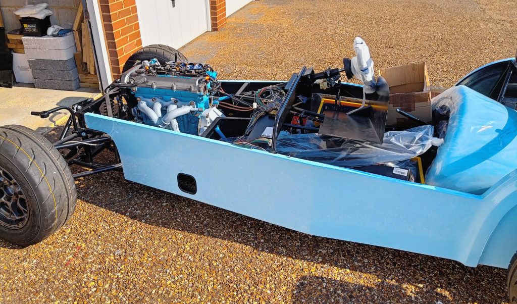 Image of car with engine installed, outside with engine loom mods in progress.