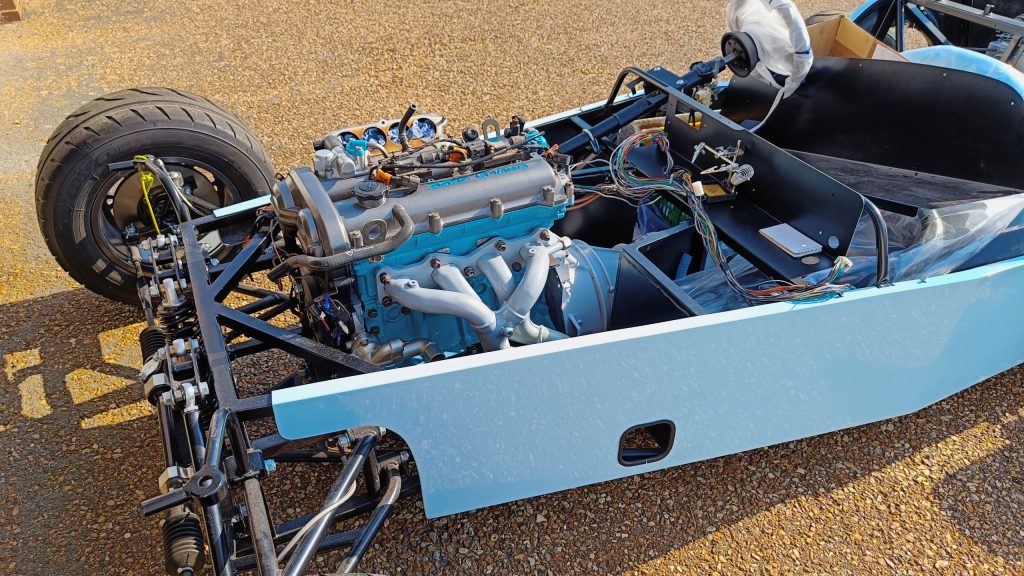 Image of car with engine installed, outside with engine loom mods in progress.