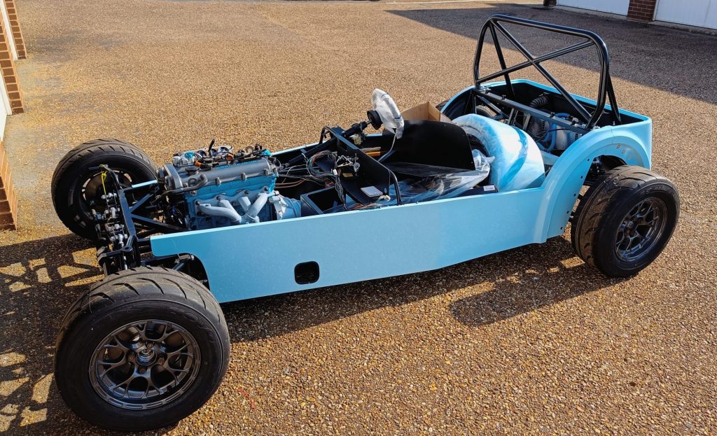 Image of car with engine installed, outside with engine loom mods in progress.