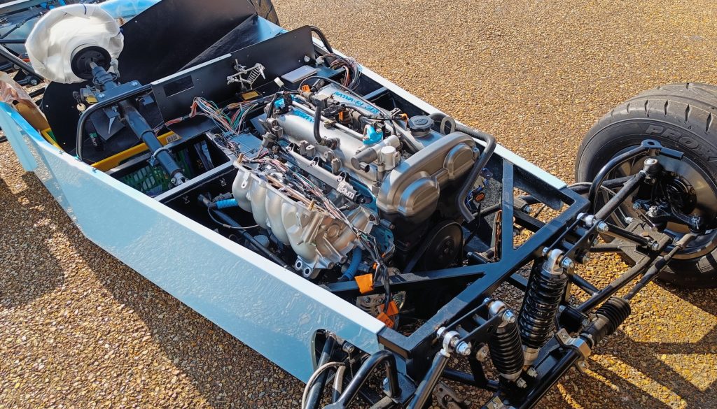 Image of car with engine installed, outside with engine loom mods in progress.