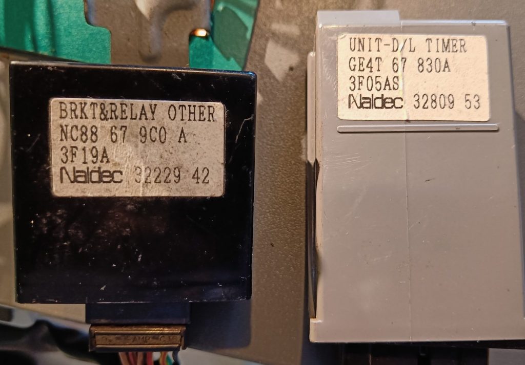 Image of two 'mystery' units in the loom. The black unit is the fog light functionality controller, and the grey the door locking timer.