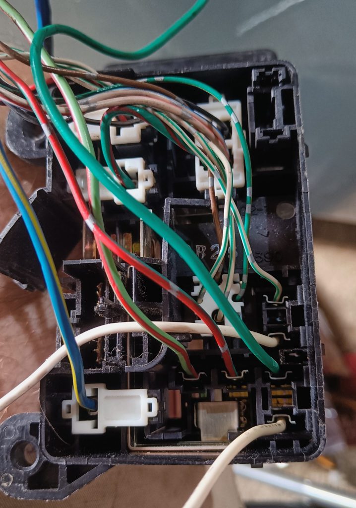 Image of underside of engine fuse box before connector X-10 has been removed.